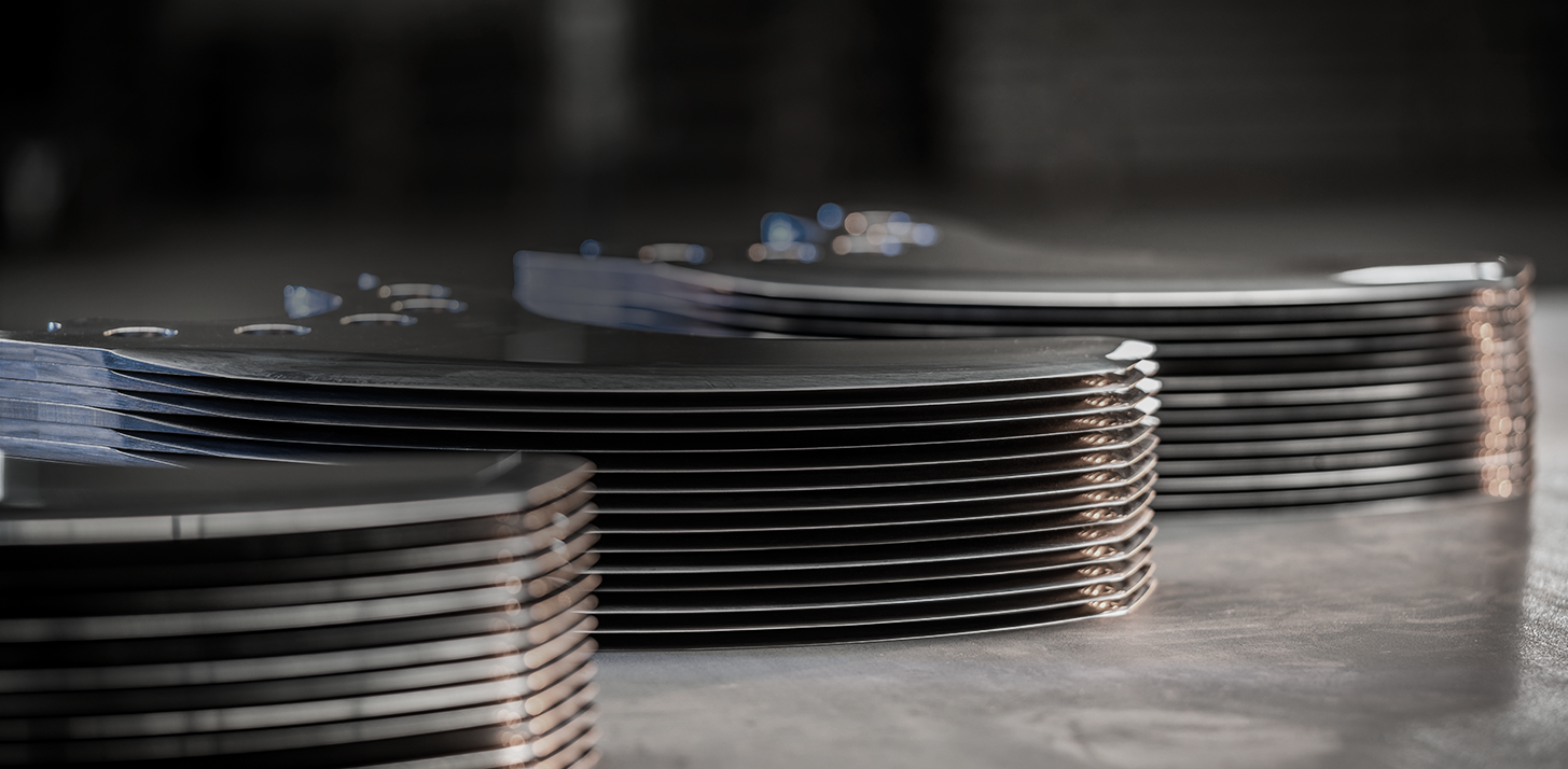 Three stacks of bowl chopper blades lie diagonally behind each other on a concrete slab.