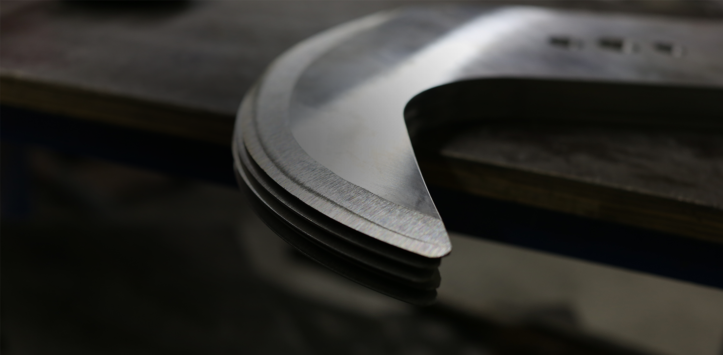 Several involute blades lie on a table, one on top of the other and slightly protruding.