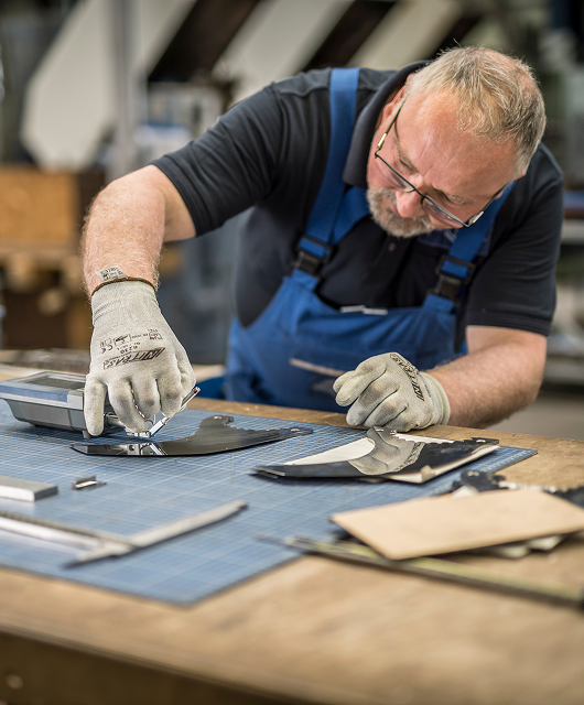 Ein Mitarbeiter von ASTOR Schneidwerkzeuge schaut sich ein Messer mit einer kleinen Lupe genauer an